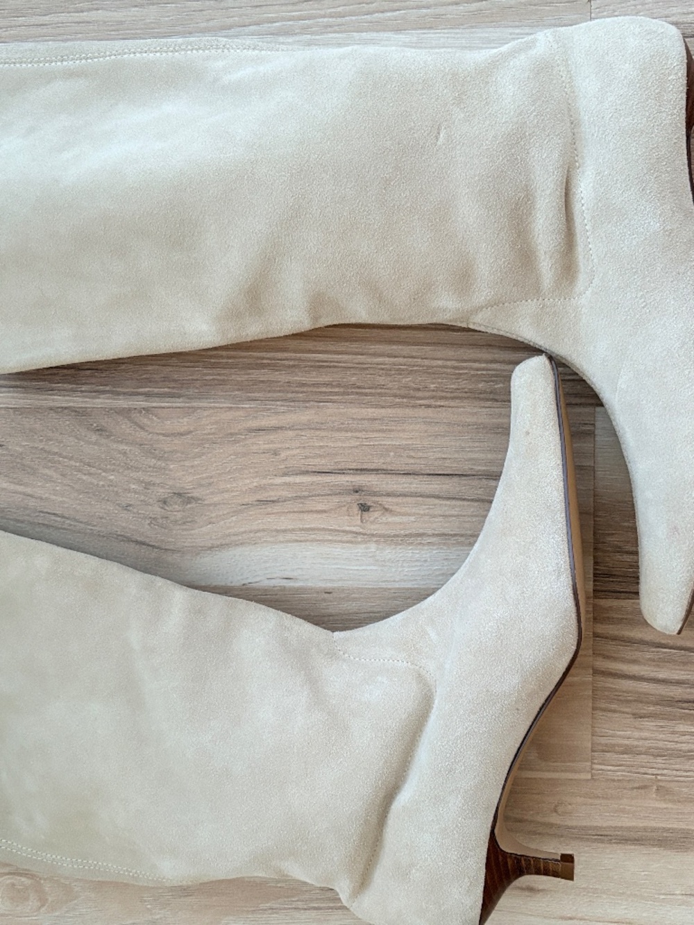 A pair of beige suede knee-high boots .